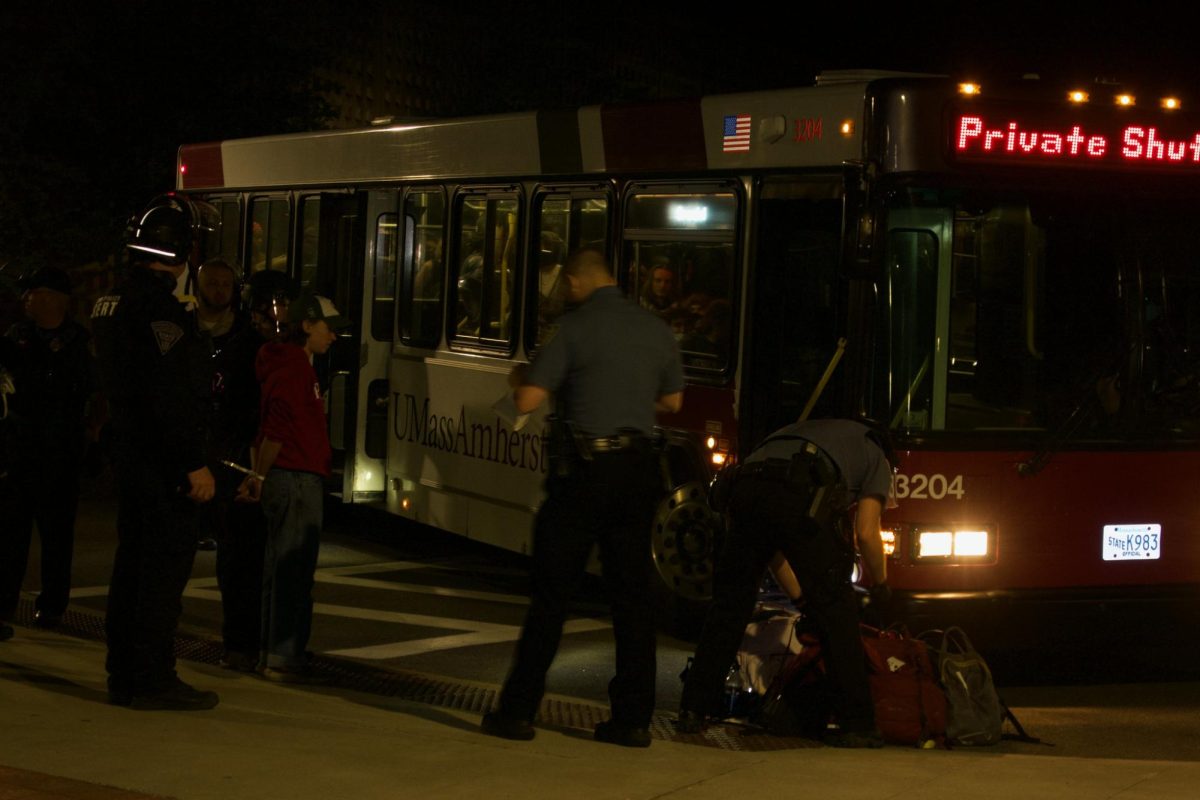 Arrested protesters are taken by police onto a university shuttle by Campus Center Way near Bowker Auditorium at 12:35 a.m. Wednesday morning.